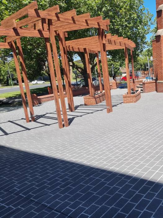 Completed concrete resurfacing in front of a red brick church with pergola structure