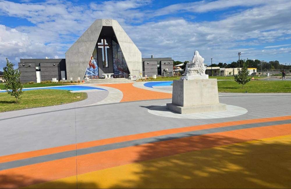 A visually striking concrete coating design at the front of a church, featuring orange, blue, and grey pathways.