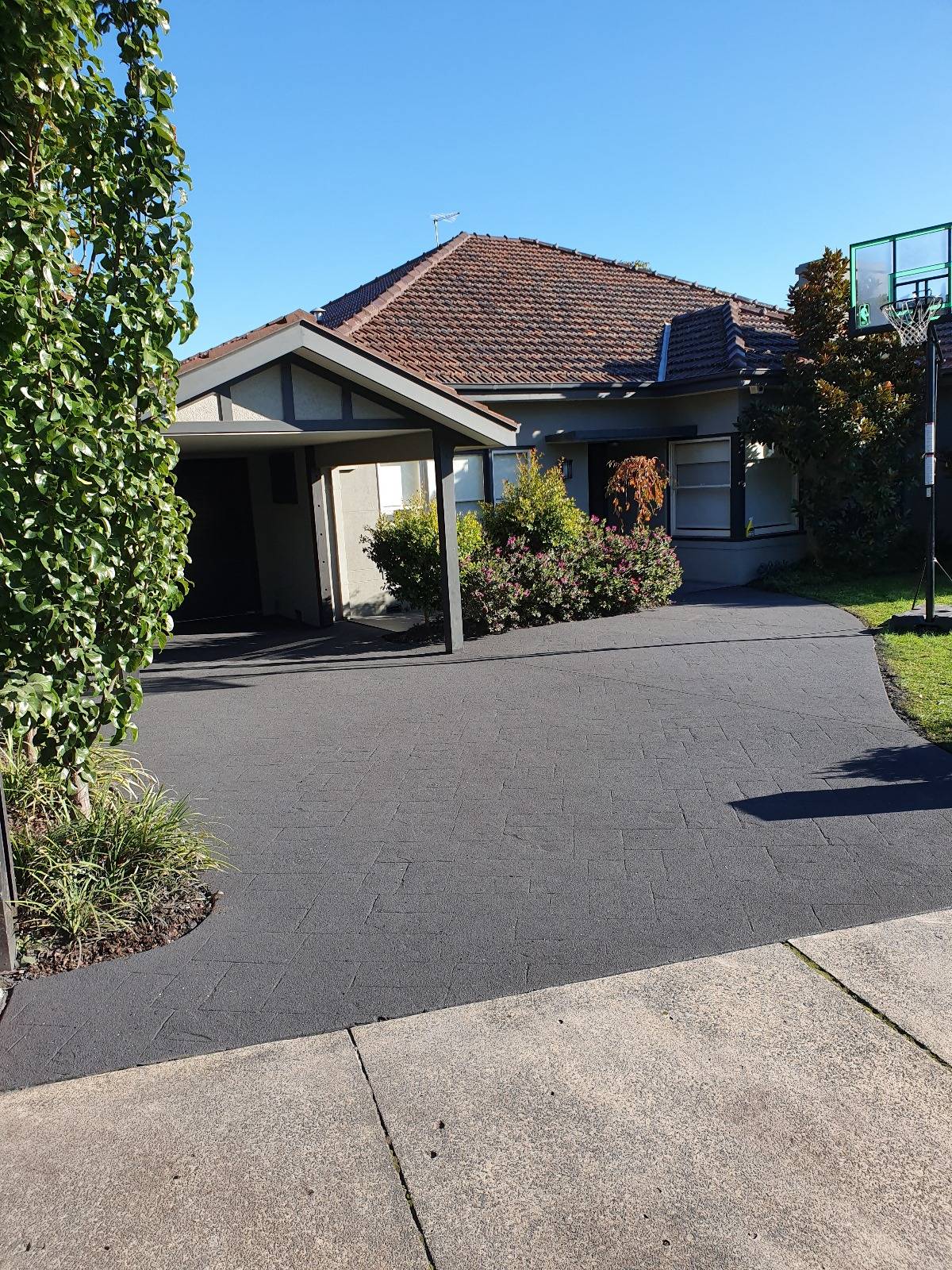 Dark resurfaced concrete driveway with a subtle stencil pattern