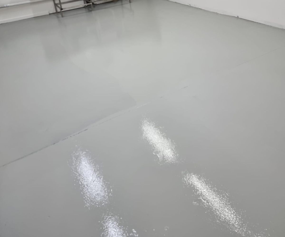 Smooth light grey epoxy floor in a commercial wet area with stainless steel sink, ideal for hygiene and easy cleaning.