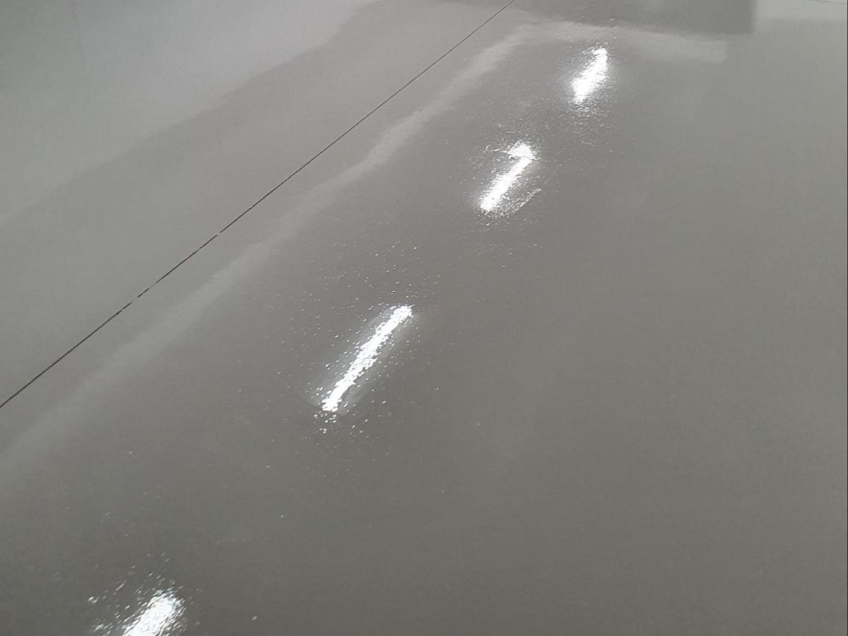 High gloss dark grey epoxy floor in a large garage, providing a modern, hard-wearing, and stain-resistant finish.