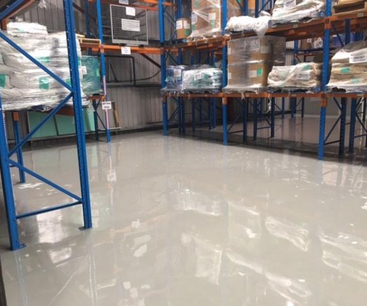 Glossy light grey epoxy flooring in a warehouse, providing a safe and easy-to-clean industrial surface.