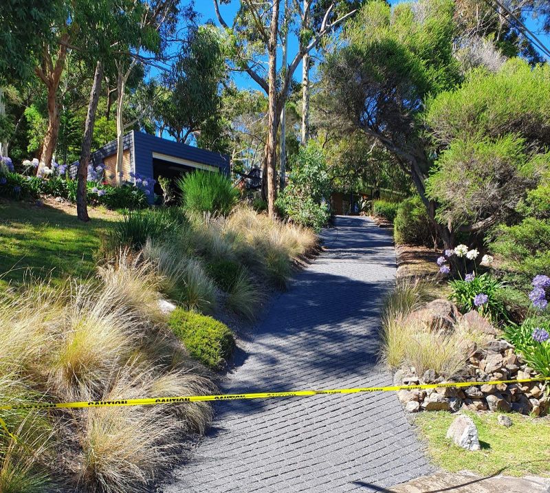 Residential driveway in Melbourne with black permeable paving, surrounded by landscaped gardens for improved drainage and aesthetic appeal.