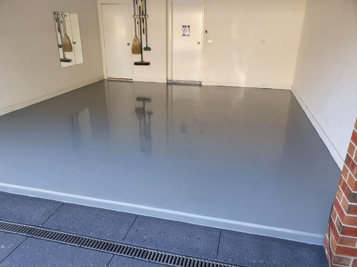 mooth light grey epoxy floor in a residential garage, delivering a durable and easy-to-maintain surface.