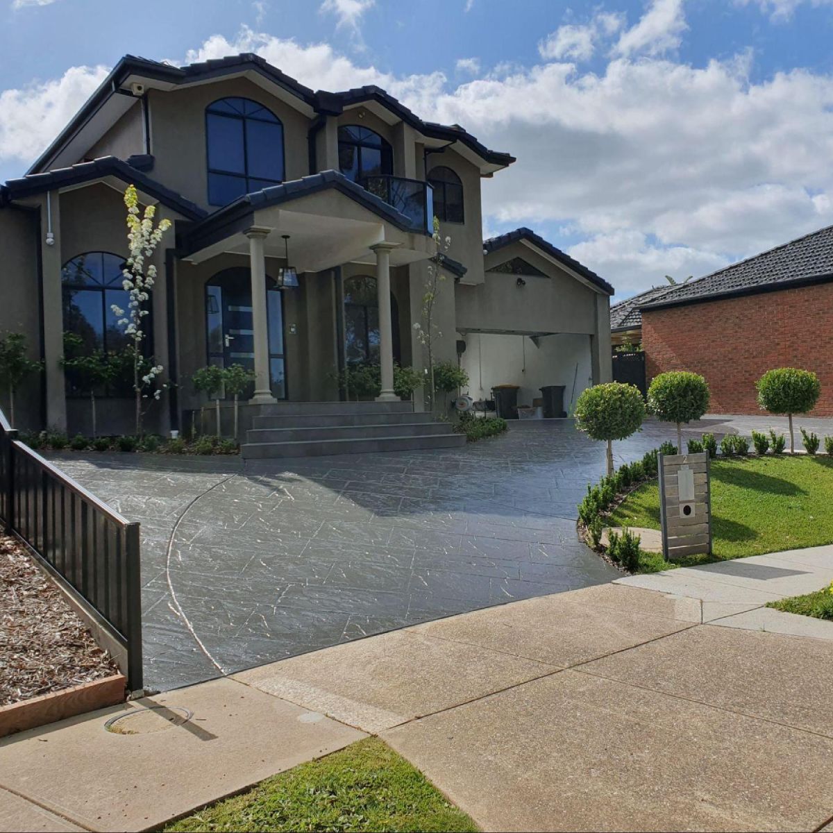 Clear and coloured decorative concrete driveway at a luxury two-storey home in Melbourne.