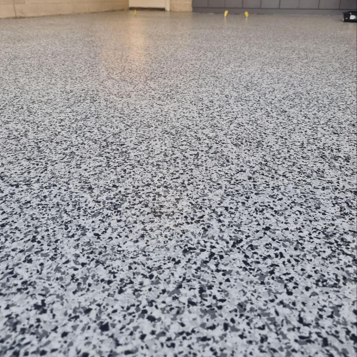 Close-up of polished epoxy interior concrete flooring with grey flake finish in Melbourne.