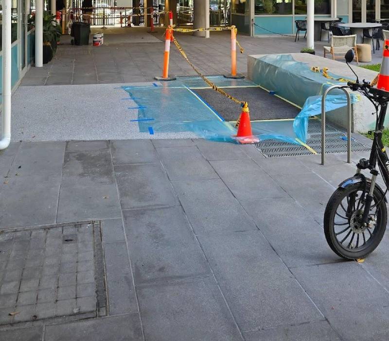 Asphalt coating applied at a commercial entry area in Melbourne, under a timber roof structure.