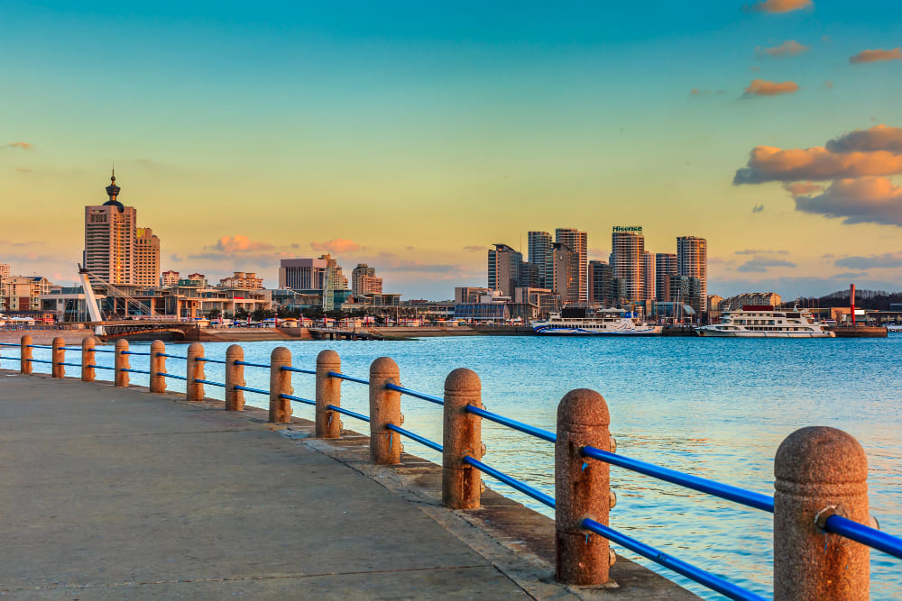 Mornington waterfront with city skyline, boats, and a seaside promenade at sunset