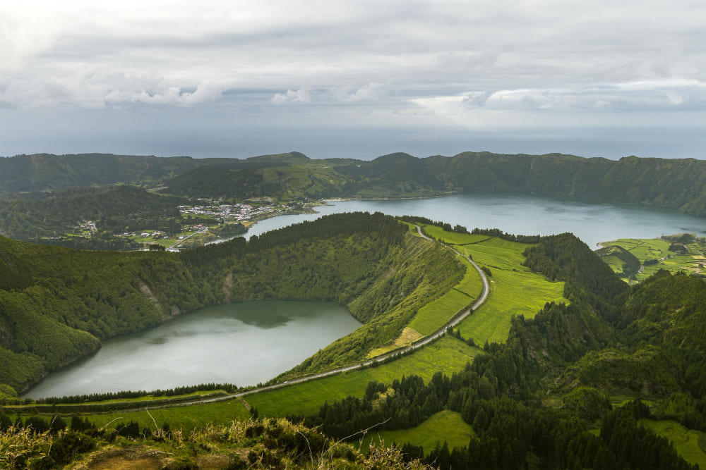 Mount Martha landscape with green hills, a coastal lake, and winding roads under cloudy skies