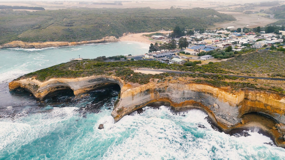 Portsea, Victoria, Australia coastal cliffs with natural rock arches, turquoise ocean, and waves along the shoreline