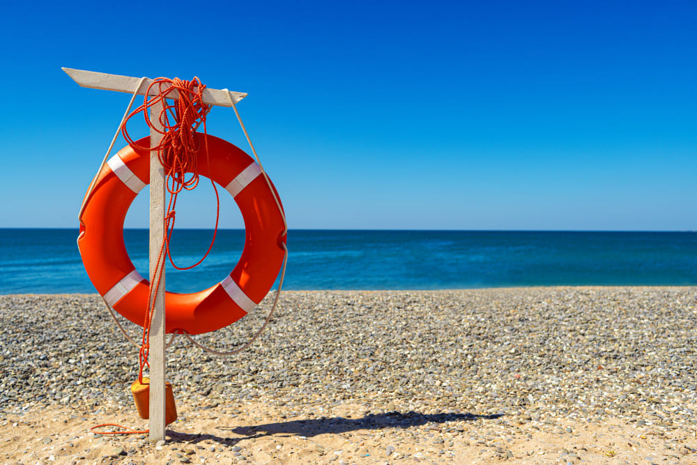 Orange life ring on Safety Beach with clear blue sea and a sunny coastal view