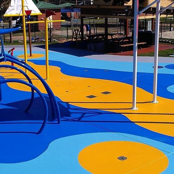 Colourful blue and yellow sport flooring with slip-resistant coating in a children’s playground area, designed for durability and safety.
